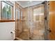 Bathroom featuring a glass shower with stone-look tile surround, mosaic floor and window with a tree view at 10756 Timothys Dr, Conifer, CO 80433