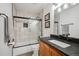 Well-lit bathroom featuring a dark vanity with a white sink, tile floors and a bathtub with glass doors at 10756 Timothys Dr, Conifer, CO 80433