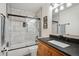 Well-lit bathroom featuring a dark vanity with a white sink, tile floors and a bathtub with glass doors at 10756 Timothys Dr, Conifer, CO 80433