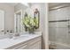 Bright bathroom features a white marble vanity, decorative mirror, and a walk-in shower with glass door at 8651 S De Gaulle Ct, Aurora, CO 80016