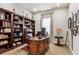 This home office has a beautiful desk, dark wood bookshelves, a leather chair, and natural light at 8651 S De Gaulle Ct, Aurora, CO 80016