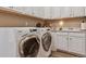 Bright laundry room with a white washer and dryer, cabinets, and a sink with a marble countertop at 8651 S De Gaulle Ct, Aurora, CO 80016