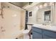 Bright bathroom featuring a shower-tub combo, blue vanity, and neutral tile flooring at 18578 E Whitaker Cir # A, Aurora, CO 80015