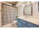 Well-lit bathroom featuring a blue vanity with ample storage and a shower-tub combination with a stylish shower curtain at 18578 E Whitaker Cir # A, Aurora, CO 80015