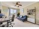 Bright bedroom features a ceiling fan, large window, futon couch, and bookshelf at 10065 Cairns Ct, Highlands Ranch, CO 80130