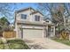 Two-story home boasts a well-manicured lawn, mature trees, brick accents, and a cozy front porch at 10065 Cairns Ct, Highlands Ranch, CO 80130
