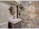 Bathroom featuring a modern vanity, frameless glass shower, and attractive neutral stone-style tiling at 2389 Nome St, Aurora, CO 80010