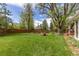 Manicured lawn with mature trees, garden boxes, and fence at 8390 E Davies Pl, Centennial, CO 80112