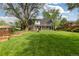 Expansive backyard featuring a large lawn, raised garden beds, mature trees, and an enclosed porch area at 8390 E Davies Pl, Centennial, CO 80112