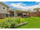 Beautifully landscaped backyard featuring a covered patio with hot tub, plus green lawn and flower beds at 10009 Dodge Dr, Northglenn, CO 80260