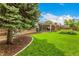 Spacious backyard with green lawn, mature trees, and covered patio for outdoor living and entertaining at 10009 Dodge Dr, Northglenn, CO 80260