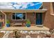 Inviting front porch with blue door, brick facade, rock landscaping, a bench and potted plants at 10009 Dodge Dr, Northglenn, CO 80260