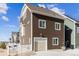 Rear exterior of brown home with a two-car garage, white fence, and low-maintenance rock landscaping at 5383 Andes St, Denver, CO 80249