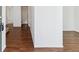 Hallway featuring wood flooring and access to multiple rooms, including a bathroom, creating an open and connected layout at 5383 Andes St, Denver, CO 80249