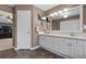 Bathroom with double vanity, large mirror, television, tile floors and adjacent bedroom at 5009 Mt Osage St, Frederick, CO 80504