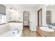 Bathroom featuring vanity, soaking tub, tile floor, decorative mirror, and walk-in closet at 1507 Alpine Ave, Berthoud, CO 80513
