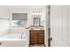 Bathroom featuring a soaking tub, a wood vanity, and a window with blinds at 1507 Alpine Ave, Berthoud, CO 80513