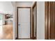 Hallway view showing an open kitchen, white interior door with dark trim, and hardwood floors at 1507 Alpine Ave, Berthoud, CO 80513