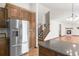 Open kitchen featuring stainless refrigerator, granite countertops, wood cabinets, and view to staircase at 1507 Alpine Ave, Berthoud, CO 80513