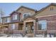 Tan and brick townhouse exterior with a small front yard and metal fence at 6448 Silver Mesa Dr # B, Highlands Ranch, CO 80130