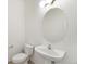 Powder room featuring a pedestal sink, oval mirror, and toilet at 6973 W Louisiana Ave # E, Denver, CO 80232