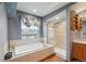 Bright bathroom with a large soaking tub, shower, and wood-look floors at 6973 W Louisiana Ave # E, Denver, CO 80232