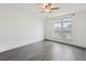 Bright bedroom with neutral walls, grey wood floors, a ceiling fan, and large window at 6973 W Louisiana Ave # E, Denver, CO 80232