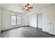 Bright bedroom has neutral walls, grey wood floors, a ceiling fan, and a white door at 6973 W Louisiana Ave # E, Denver, CO 80232