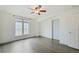 Bright bedroom features neutral walls, a ceiling fan, grey wood floors, and a white door at 6973 W Louisiana Ave # E, Denver, CO 80232