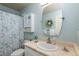Well-lit bathroom with vanity, decorative mirror, and shower with floral curtain at 8318 Devinney Ct, Arvada, CO 80005