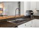 Close-up of kitchen featuring a stainless steel sink, granite countertops, and tile backsplash at 8318 Devinney Ct, Arvada, CO 80005