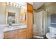 Bathroom featuring wood cabinets, a vanity with gold hardware, and a glass-enclosed shower at 24999 Grandview Ave, Golden, CO 80401