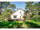 Two-story home with a deck, surrounded by lush greenery and mature trees at 24999 Grandview Ave, Golden, CO 80401