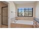 Bathroom featuring a soaking tub, adjacent shower, vanity with black countertop and a large window offering natural light at 1530 S Quebec Way # 34, Denver, CO 80231