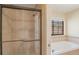 Tiled shower with glass door, next to a soaking tub and window providing natural light to the neutral toned bathroom at 1530 S Quebec Way # 34, Denver, CO 80231