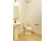 A simple powder bathroom with a white toilet and white pedestal sink sits on wood-look floors at 5937 N Orleans St, Aurora, CO 80019