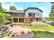 A spacious backyard featuring a large deck, brick patio, and mature landscaping at 3253 S King Way, Denver, CO 80236