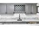 A close-up view of the wet bar which features marble countertops and gray cabinetry at 3253 S King Way, Denver, CO 80236
