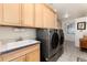 This laundry room features a utility sink, updated cabinets, and a modern washer and dryer at 8198 S Sicily Ct, Aurora, CO 80016