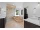 Luxurious bathroom featuring a soaking tub, glass enclosed shower, and dual vanity sinks with modern fixtures at 7071 Turweston Ln, Castle Pines, CO 80108