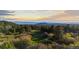 Panoramic view of a golf course surrounded by lush trees and distant mountains under a colorful sky at 7071 Turweston Ln, Castle Pines, CO 80108
