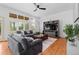 Bright living room featuring hardwood floors, ceiling fan, large windows, and entertainment center at 7071 Turweston Ln, Castle Pines, CO 80108