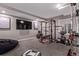 Home gym featuring weights, a squat rack, workout bench, and a large television at 12183 W Chenango Dr, Morrison, CO 80465