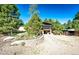 Exterior view of backyard featuring lush landscaping, gravel parking, screened-in porch, and mature trees at 1059 S Elbert St, Elizabeth, CO 80107