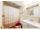 Updated bathroom featuring bright vanity, mirrored cabinet, shower with a patterned curtain and red toilet seat at 1059 S Elbert St, Elizabeth, CO 80107