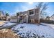 Charming gray two-story home featuring a covered front porch and snow-covered yard at 15716 E Temple Pl, Aurora, CO 80015