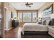 Bright bedroom featuring hardwood floors, a ceiling fan, and a large window with plantation shutters at 22455 E Plymouth Cir, Aurora, CO 80016