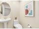 Bright half bathroom featuring a pedestal sink and a round mirror at 1827 N Grant St # 604, Denver, CO 80203
