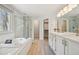 Bright bathroom featuring a soaking tub, glass-enclosed shower, dual vanities, and stylish tile work at 6468 S Forest St, Centennial, CO 80121