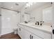 Modern bathroom with double vanity, white subway tile shower and dark fixtures at 5583 Riverbend Ave, Firestone, CO 80504